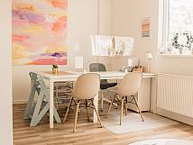 Lichtdurchfluteter Raum mit Schreibtisch, Stühlen und abstraktem Gemälde an der Wand