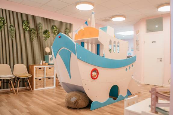 Innenraum mit fantasievollem Holzspielschiff, Stühlen und gemütlicher Atmosphäre