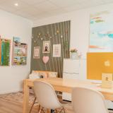 Innenraum mit Tisch, Stühlen, Kinderecke, farbigen Möbeln und kreativer Wandgestaltung